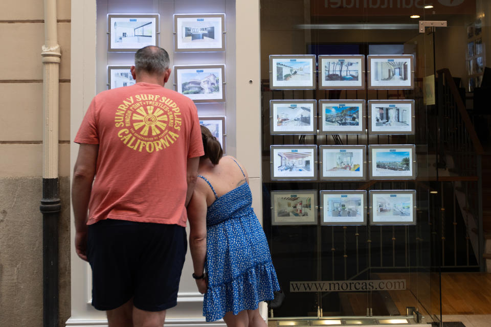 PALMA DE MALLORCA, MAJORCA BALE, SPAIN - APRIL 24: Two people look at advertisements for homes for sale in a real estate agency on April 16, 2024, in Palma de Mallorca, Mallorca, Balearic Islands, Spain. On April 16, the Plenary of the Parliament of the Balearic Islands passed a law, stemming from Decree Law 6/2023, of October 2, on urgent housing measures, which introduced measures to encourage new housing on the market in the urban areas of the municipalities of the Balearic Islands. The Official Association of Real Estate Agents of the Balearic Islands (COAPI) and the Balearic real estate alliance ABINI have celebrated the approval. (Photo By Tomas Moya/Europa Press via Getty Images)