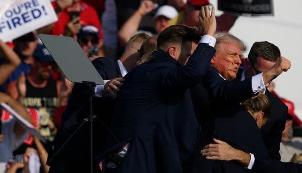 BUTLER, PENNSYLVANIA - JULY 13: Republican presidential candidate, former U.S. President Donald Trump is whisked away by Secret Service after shots rang out at a campaign rally at Butler Farm Show Inc. on July 13, 2024 in Butler, Pennsylvania. Trump slumped and injuries were visible to the side of his head. Butler County district attorney Richard Goldinger said the shooter and one audience member are dead and another was injured. (Photo by Jeff Swensen/Getty Images)