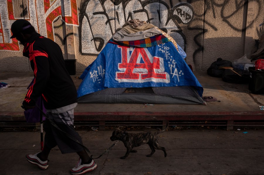 FILE - A man walks past a homeless encampment in downtown Los Angeles, Wednesday, Oct. 25, 2023. (AP Photo/Jae C. Hong, File)