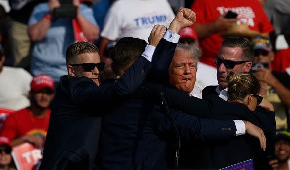 BUTLER, PENNSYLVANIA - JULY 13: Republican presidential candidate, former U.S. President Donald Trump is whisked away by Secret Service after shots rang out at a campaign rally at Butler Farm Show Inc. on July 13, 2024 in Butler, Pennsylvania. Trump slumped and injuries were visible to the side of his head. Butler County district attorney Richard Goldinger said the shooter and one audience member are dead and another was injured. (Photo by Jeff Swensen/Getty Images)