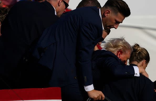 BUTLER, PENNSYLVANIA - JULY 13: Republican presidential candidate, former U.S. President Donald Trump is whisked away by Secret Service after shots rang out at a campaign rally at Butler Farm Show Inc. on July 13, 2024 in Butler, Pennsylvania. Trump slumped and injuries were visible to the side of his head. Butler County district attorney Richard Goldinger said the shooter and one audience member are dead and another was injured. (Photo by Jeff Swensen/Getty Images)