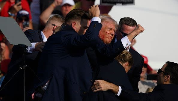 BUTLER, PENNSYLVANIA - JULY 13: Republican presidential candidate, former U.S. President Donald Trump is whisked away by Secret Service after shots rang out at a campaign rally at Butler Farm Show Inc. on July 13, 2024 in Butler, Pennsylvania. Trump slumped and injuries were visible to the side of his head. Butler County district attorney Richard Goldinger said the shooter and one audience member are dead and another was injured. (Photo by Jeff Swensen/Getty Images)