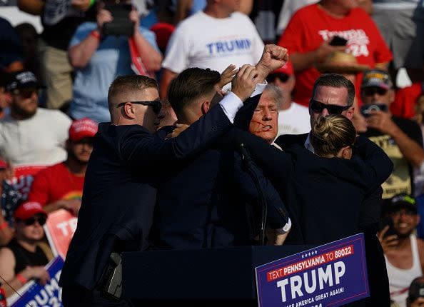 BUTLER, PENNSYLVANIA - JULY 13: Republican presidential candidate, former U.S. President Donald Trump is whisked away by Secret Service after shots rang out at a campaign rally at Butler Farm Show Inc. on July 13, 2024 in Butler, Pennsylvania. Trump slumped and injuries were visible to the side of his head. Butler County district attorney Richard Goldinger said the shooter and one audience member are dead and another was injured. (Photo by Jeff Swensen/Getty Images)