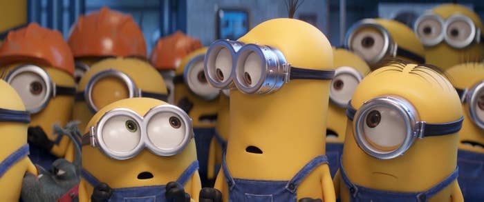 Minions from the movie "Minions" stand together with surprised expressions, all wearing blue overalls and goggles