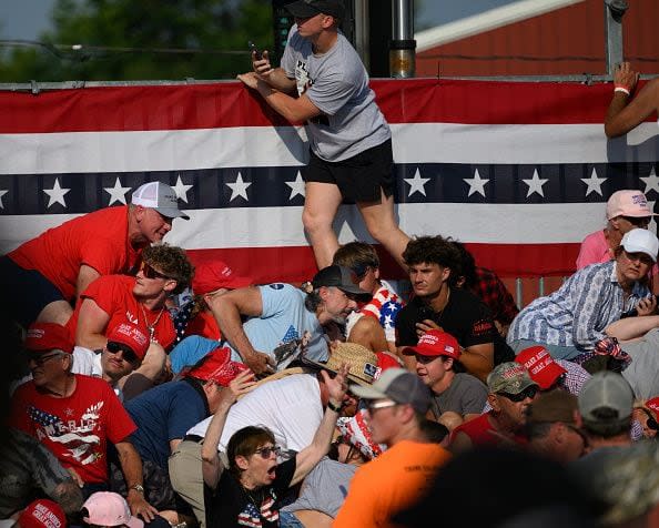 BUTLER, PENNSYLVANIA - JULY 13: Attendees duck from gunfire at a campaign rally for Republican presidential candidate, former U.S. President Donald Trump at Butler Farm Show Inc. on July 13, 2024 in Butler, Pennsylvania. Trump slumped before being whisked away by Secret Service with injuries visible to the side of his head. Butler County district attorney Richard Goldinger said the shooter and one audience member are dead and another was injured. (Photo by Jeff Swensen/Getty Images)