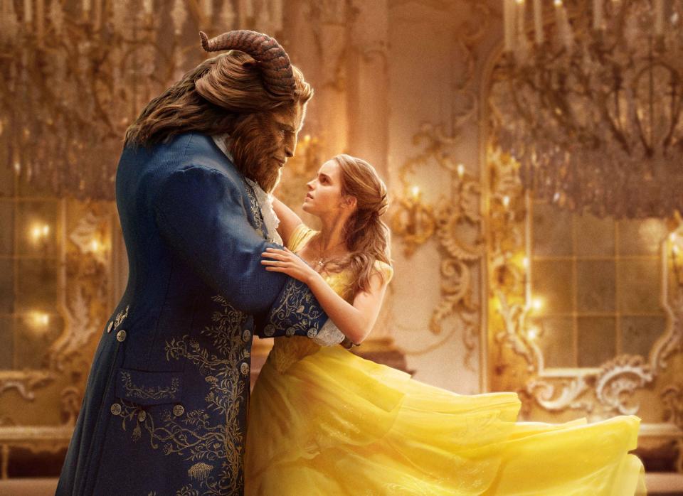 Beast in an ornate blue coat and Belle in a flowing yellow gown dance in a grand ballroom from Beauty and the Beast