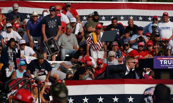 BUTLER, PENNSYLVANIA - JULY 13: Republican presidential candidate, former U.S. President Donald Trump is swarmed by Secret Service after gunshots rang out at a rally at Butler Farm Show Inc. on July 13, 2024 in Butler, Pennsylvania. Trump slumped before being whisked away with injuries visible to the side of his head. Butler County district attorney Richard Goldinger said the shooter and one audience member are dead and another was injured. (Photo by Jeff Swensen/Getty Images)